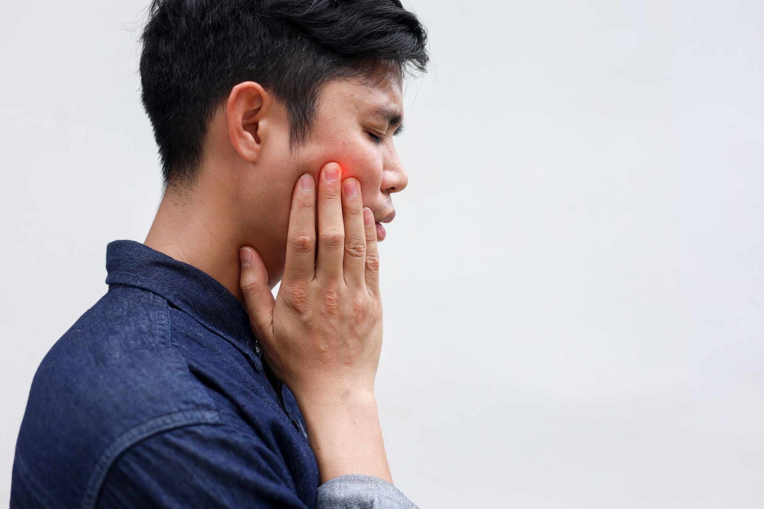 a man massaging his painful cheek because of TMJ pain