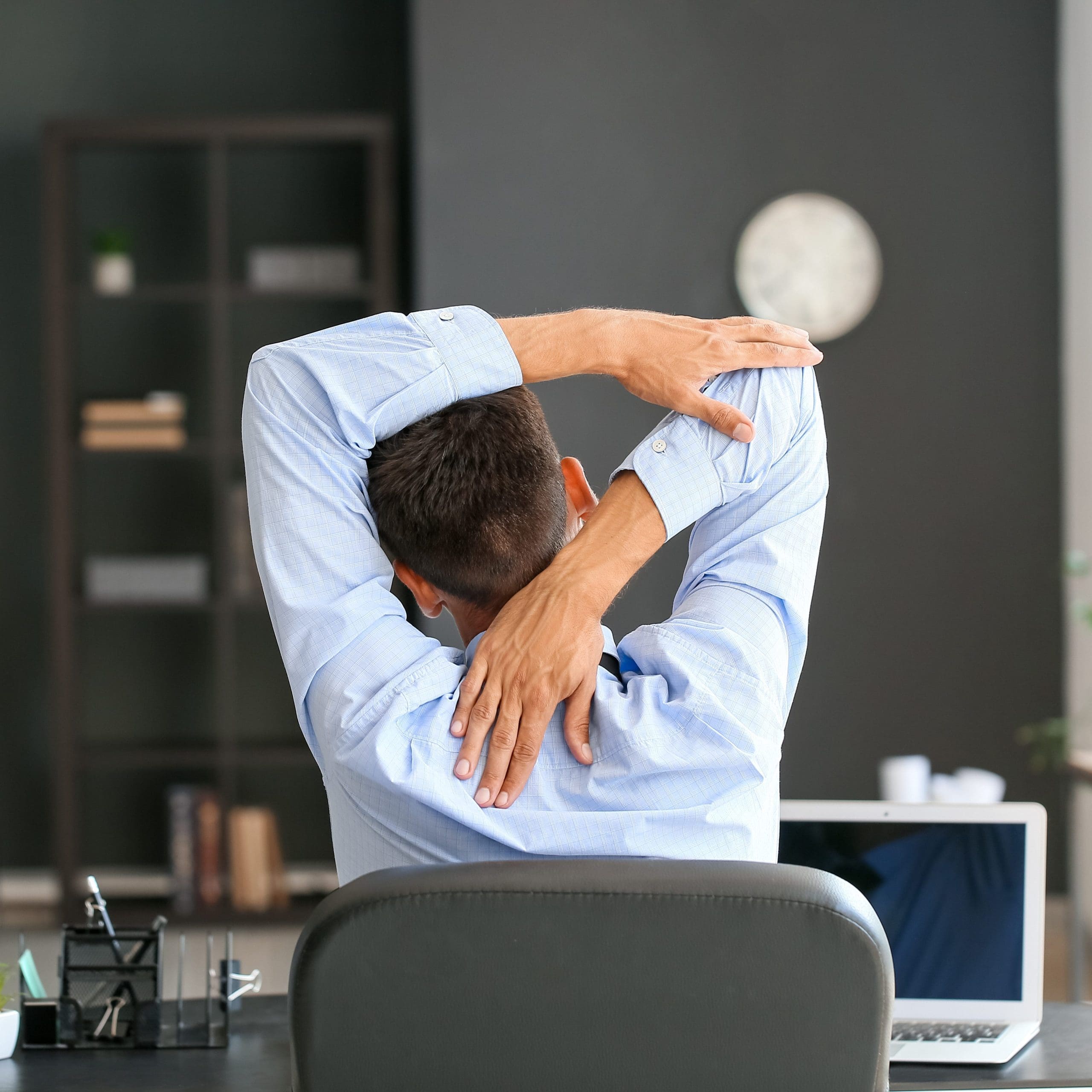 Young businessman stretching his spine while working in office.