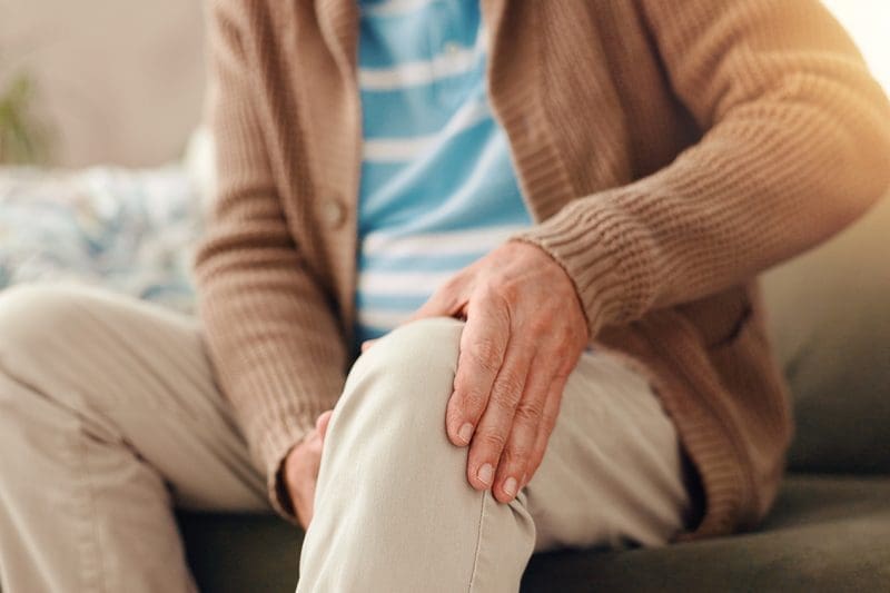 A man holding his knee because of joint pain.